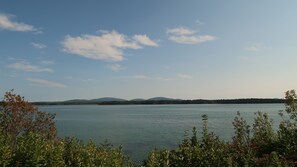 A calm lake with mountains in the background and some vegetation in the foreground.
