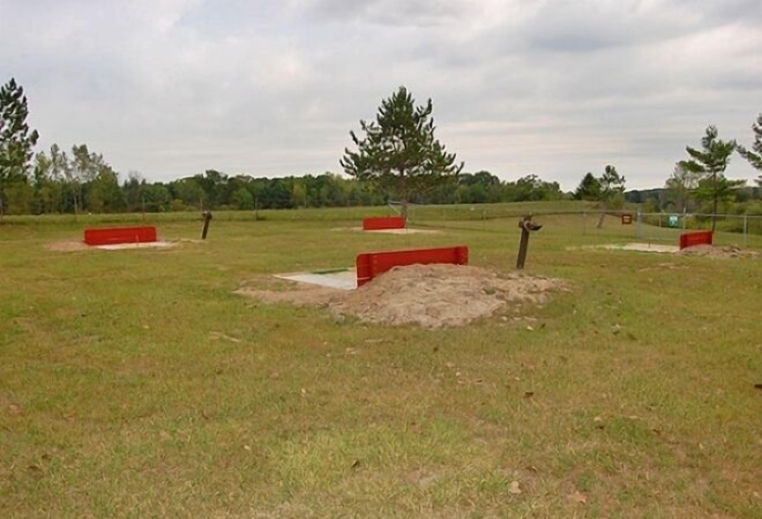 An open field with red barriers and a single tree.