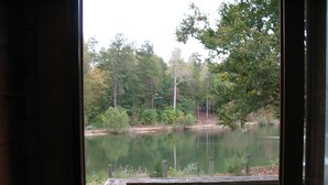 A view from a window overlooking a calm lake surrounded by trees. - Forest Lake RV & Camping Resort (Advance)