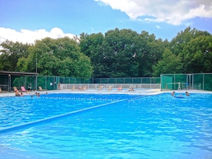 A swimming pool with multiple lanes, surrounded by a fence and trees in the background. - Lake Myers RV & Camping Resort (Mocksville)