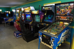 A row of arcade games including 'Road Show' and 'Midway' machines in a room with teal walls. - Twin Lakes RV & Camping Resort (Chocowinity)