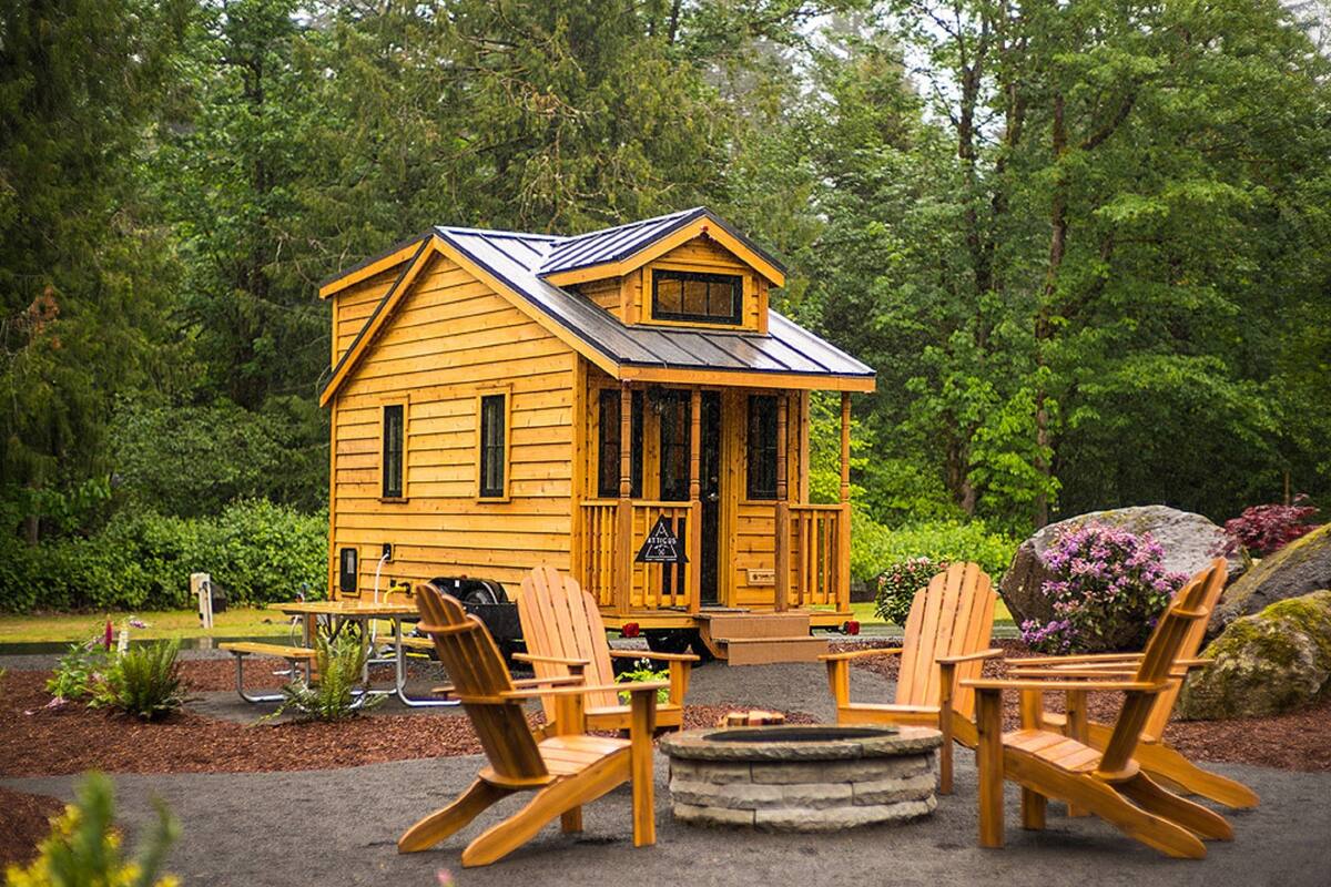 A wooden cabin with a porch, surrounded by greenery.