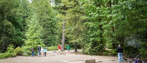 A park with a paved area, trees, and a bicycle parked by the roadside.