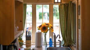 A kitchen with a window, a sink, a vase with sunflowers, and a Ginsu knife block. - Mt Hood Village RV Resort (Welches)