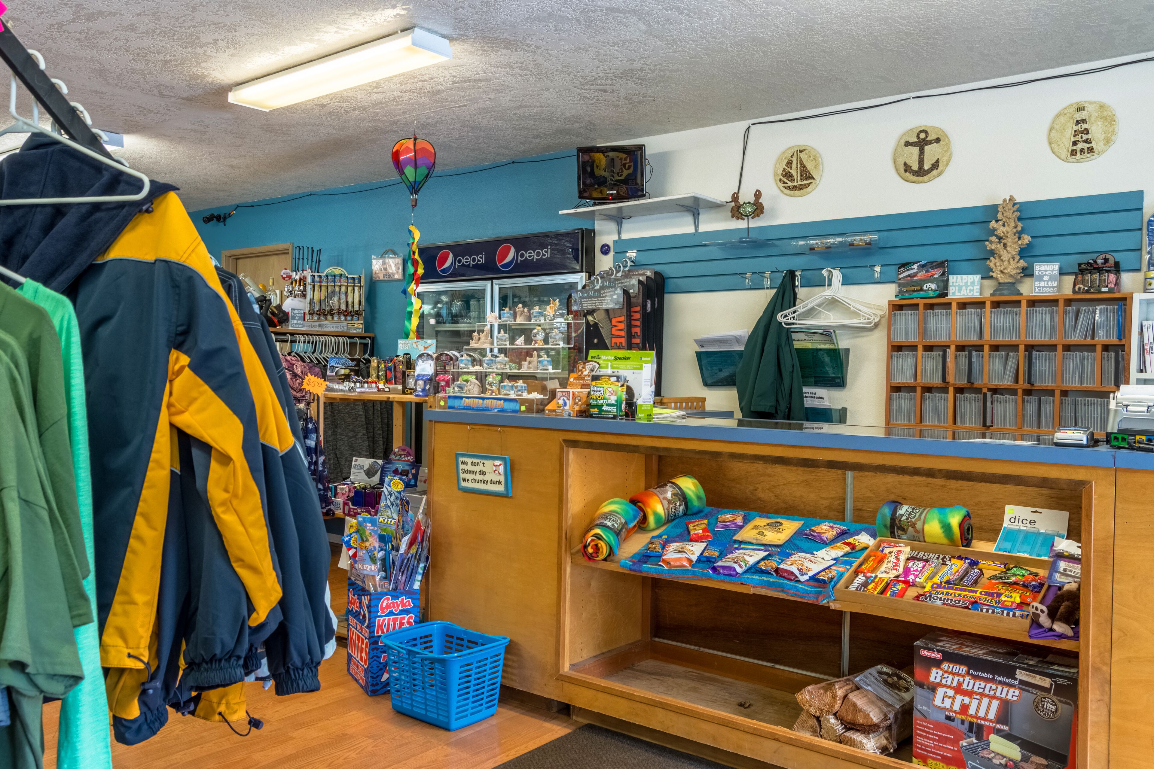 A small, well-organized store with various items on display, including snacks, drinks, and clothing.