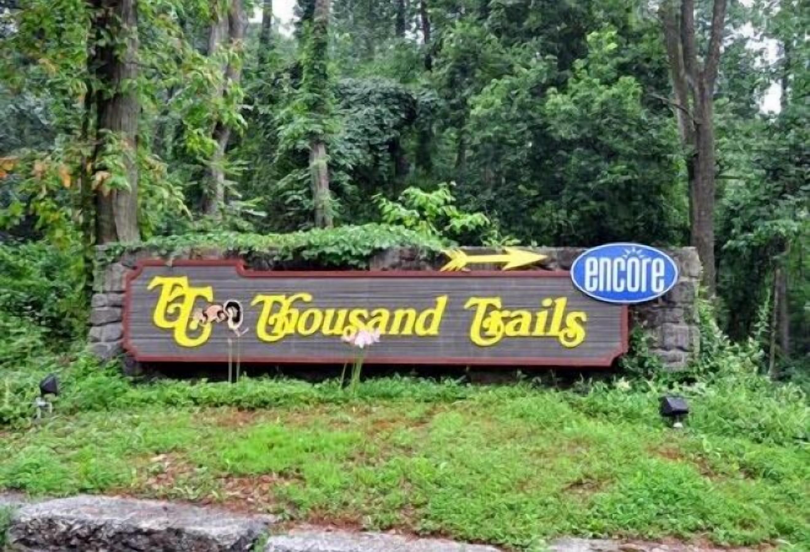 A wooden sign with the text "T&T Thousand Trails" and a logo for "Encore."