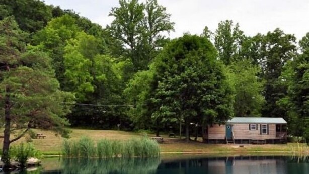 A cabin by a lake surrounded by dense trees. - Spring Gulch RV Campground (New Holland)