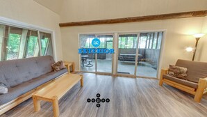A spacious living area with a sofa, a chair, and a table. There is a sliding glass door leading to an outdoor patio. - Spring Gulch RV Campground (New Holland)