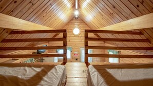An attic bedroom with wooden beams, a skylight, and a view of the outside. - Spring Gulch RV Campground (New Holland)