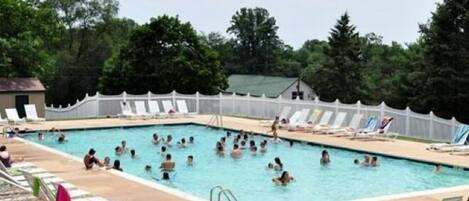Una piscina con múltiples carriles, rodeada de sillas de descanso y sombrillas.
