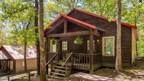 Un chalet rustique doté d’une véranda, d’un escalier en bois et d’une table de pique-nique.