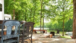 An outdoor patio area with stone flooring, metal chairs, and a table. - Natchez Trace RV Campground (Hohenwald)