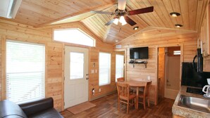 A wooden cabin interior with a dining area, kitchen, and seating area. - Lake Conroe RV & Camping Resort (Willis)