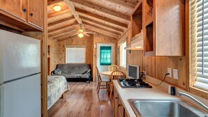 A compact kitchen with wooden cabinets, a dining area with a table and chairs, a built-in stove, and a refrigerator. - Lake Conroe RV & Camping Resort (Willis)