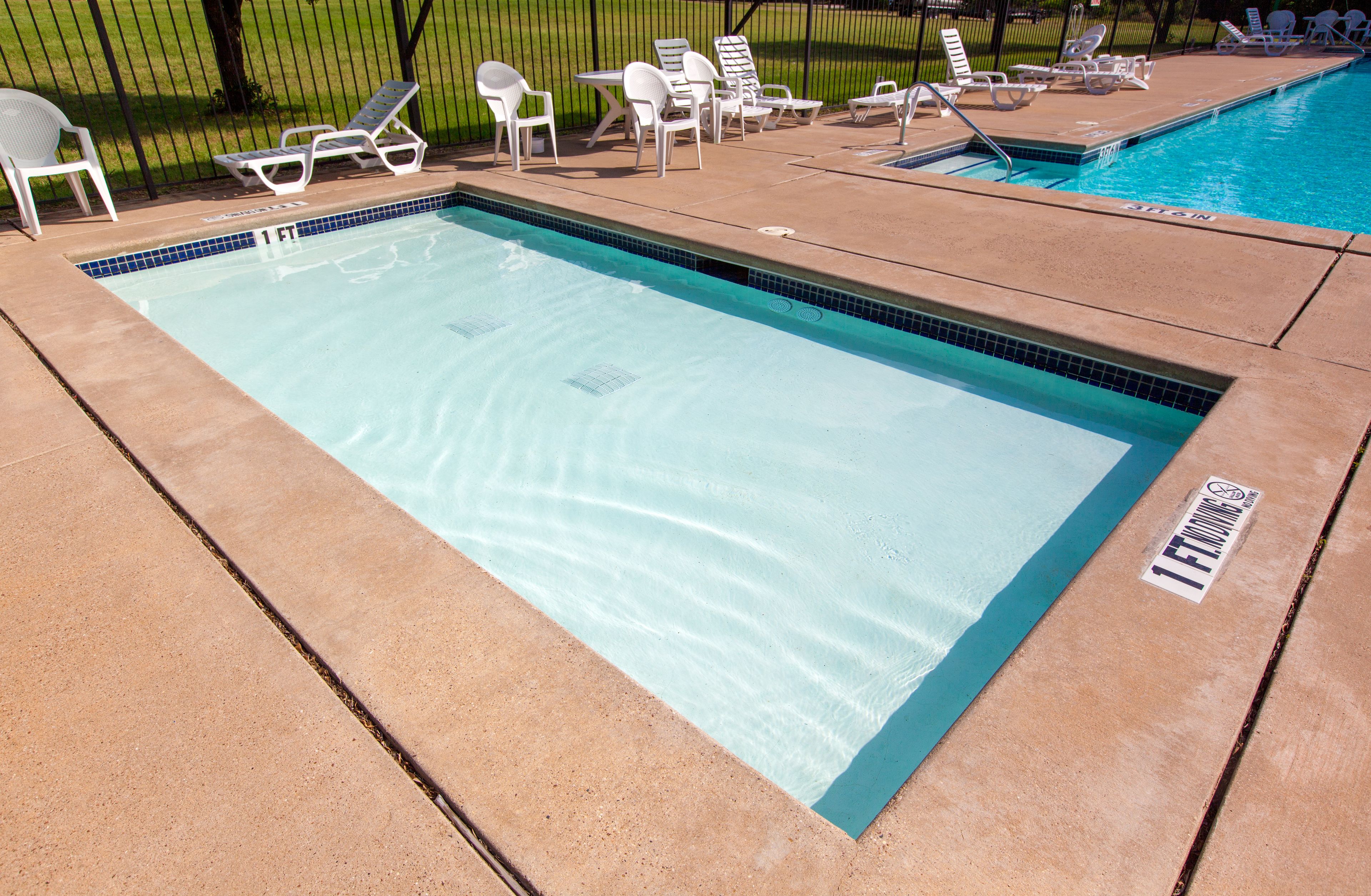 A rectangular pool with a tiled edge, surrounded by lounge chairs and a small table.