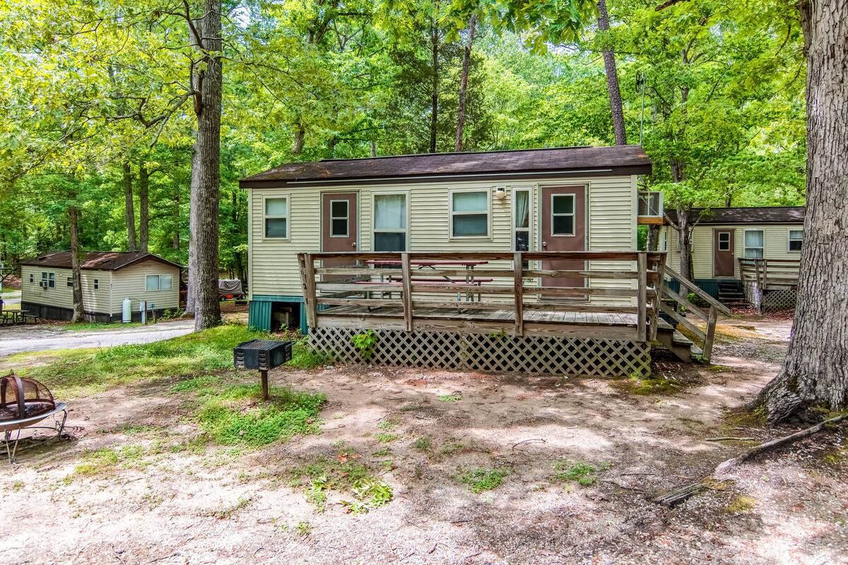 A mobile home with a fenced deck, surrounded by trees.