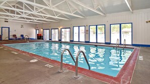 An indoor swimming pool with clear water, metal handrails, and a high ceiling with white beams. - Williamsburg RV & Camping Resort (Williamsburg)