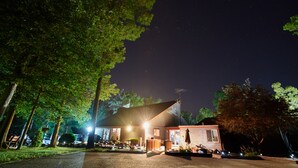 A small, single-story building with a sloped roof, surrounded by trees and a gravel driveway. - Williamsburg RV & Camping Resort (Williamsburg)
