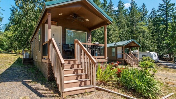 A cabin with a porch, wooden stairs, and a covered outdoor seating area. - Chehalis RV & Camping Resort (Chehalis)