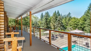 A wooden deck with a view of a pool and outdoor seating area. - Chehalis RV & Camping Resort (Chehalis)