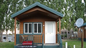 A small cabin with a front porch, a door, and a grill.