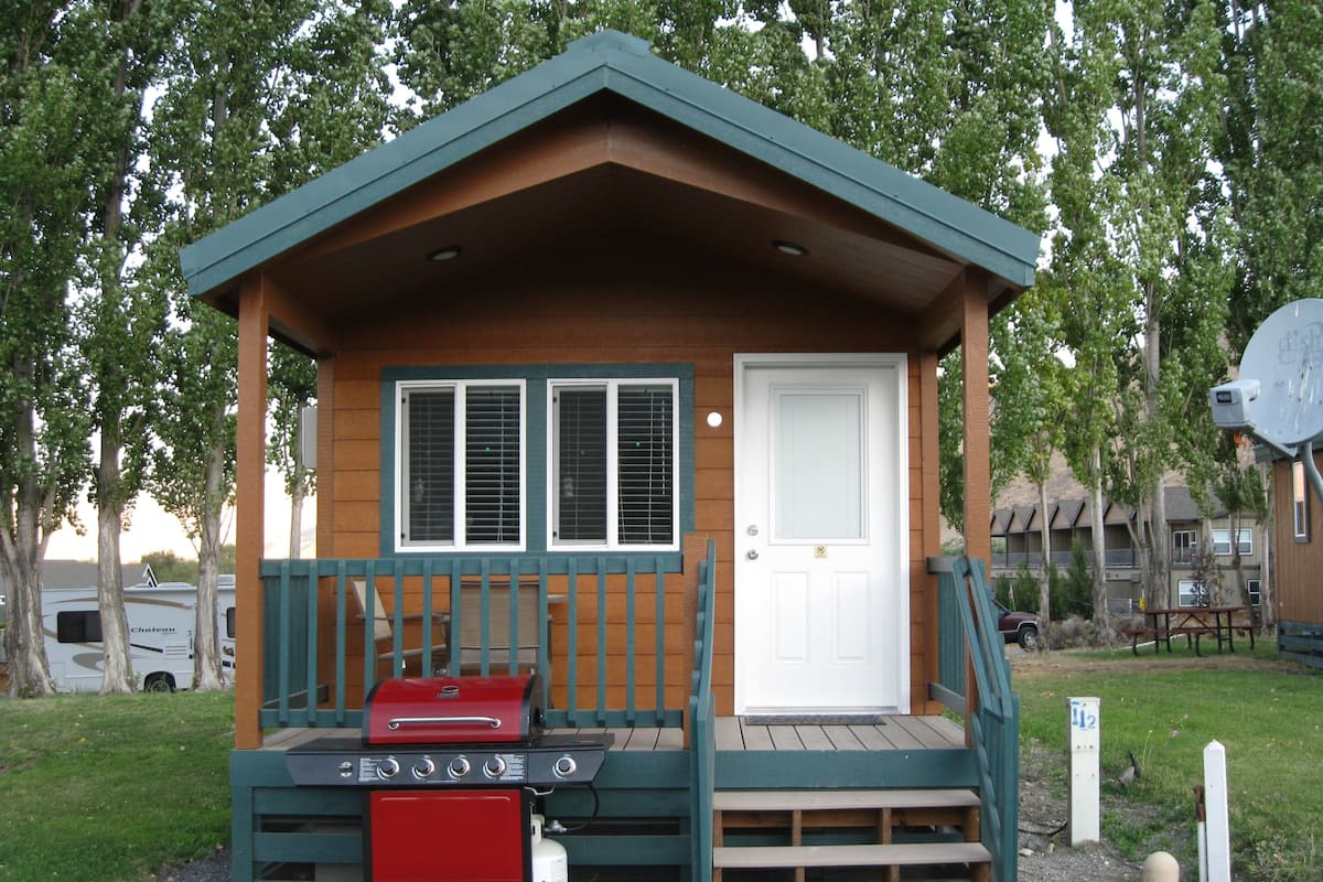 A small cabin with a front porch, a door, and a grill.