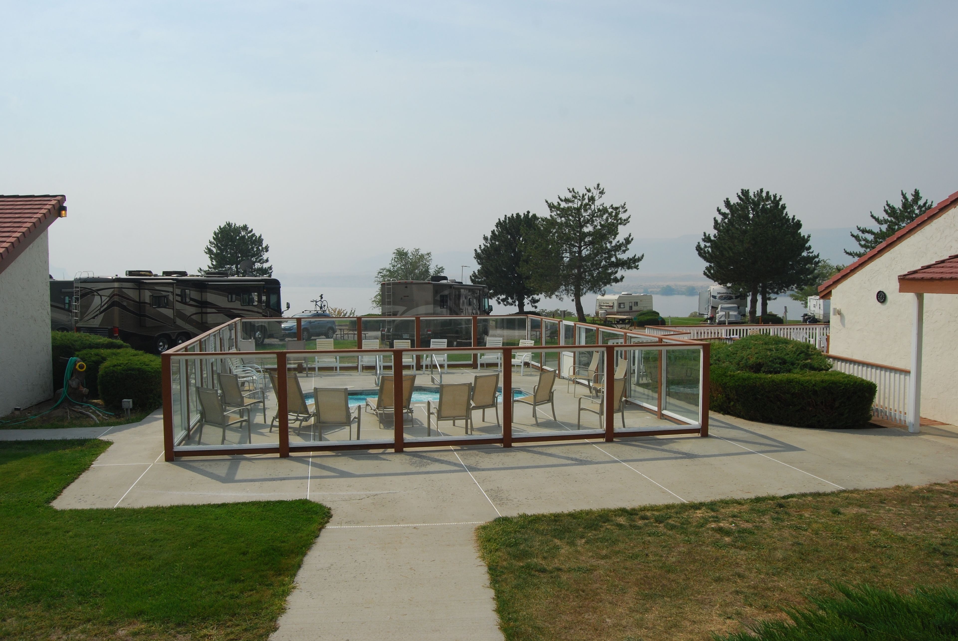 A glass-enclosed outdoor area with a pool, chairs, and a view of the sea.
