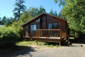 A wooden cabin with a porch and a satellite dish. - La Conner RV & Camping Resort (La Conner)