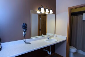 A bathroom with a white sink, a mirror, and a hairdryer on the wall. - Leavenworth RV Campground (Leavenworth)