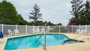 A rectangular swimming pool with a metal ladder, surrounded by white fences and chairs. - Long Beach RV & Camping Resort (Ilwaco)