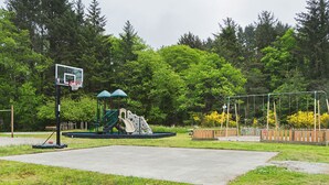 A playground with a basketball hoop, slides, and swings. - Long Beach RV & Camping Resort (Ilwaco)