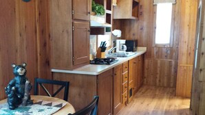 A wooden interior with a kitchen area including a stove, sink, and cabinets. - Mount Vernon RV Campground (Bow)
