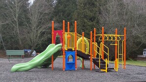 A playground with a slide, climbing structures, and a bench. - Mount Vernon RV Campground (Bow)