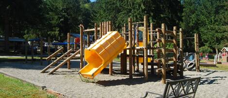 A playground with a yellow slide and climbing structures.