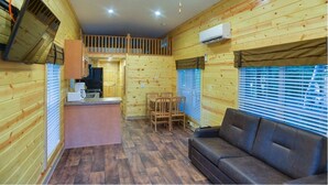 Una cabaña acogedora con interior de madera, un comedor y un sofá.