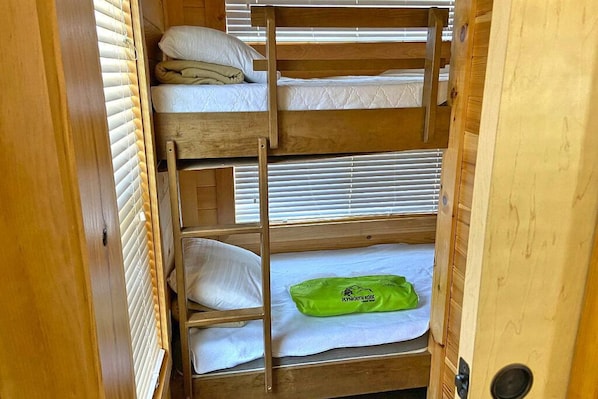 A bunk bed room with wooden frames and white bedding.