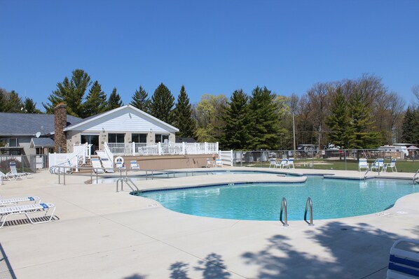 A swimming pool with lounge chairs and a covered area.