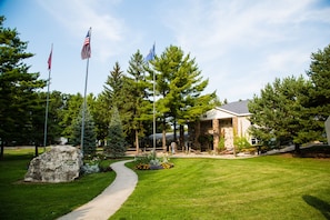 A building with a stone facade, a paved driveway, and a flagpole with multiple flags. - Plymouth Rock Camping Resort (Plymouth)