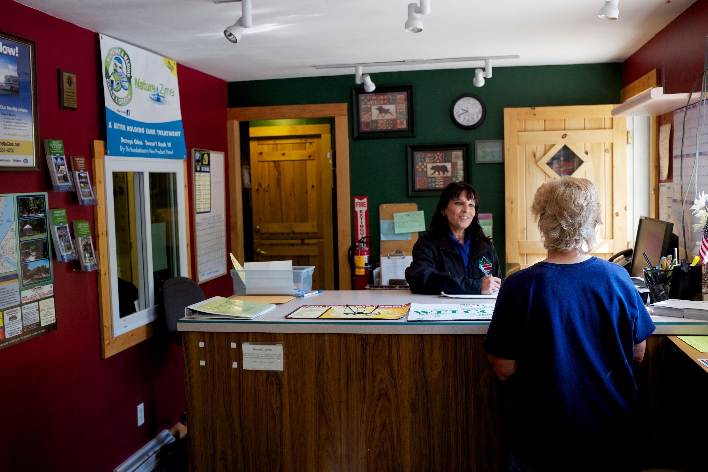 A reception desk with informational posters, a wooden counter, and a green wall.