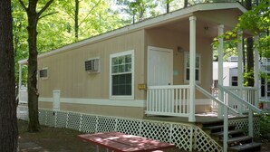 A mobile home with a porch, a staircase, and a picnic table. - Tranquil Timbers Camping Resort (Sturgeon Bay)