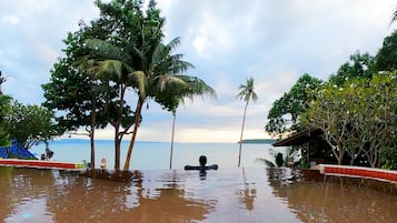 A flooded outdoor area with palm trees and a view of the sea.