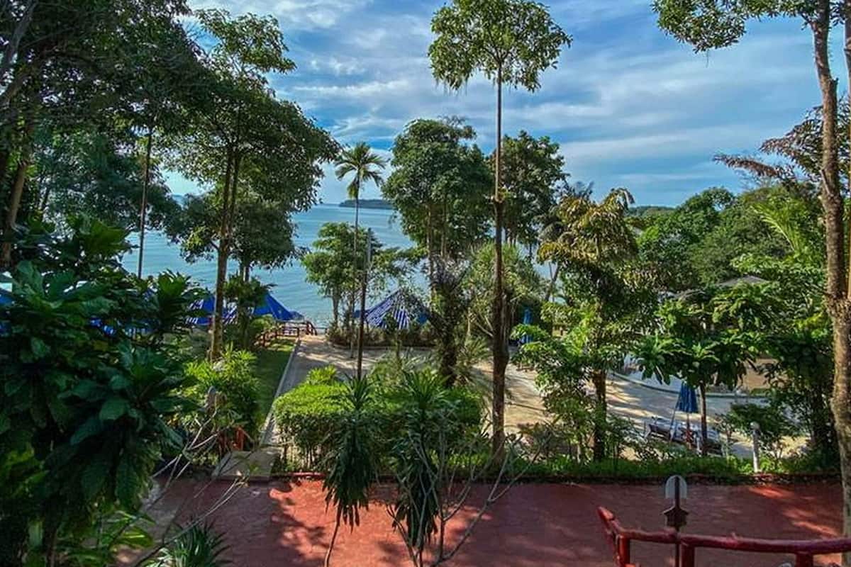 Un complexe hôtelier tropical offrant une vue sur la mer, entouré d’une végétation luxuriante et de palmiers.