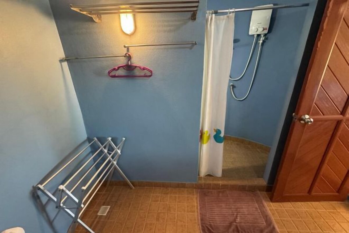 Ett badrum med en handduksställning, en duschdraperi och en dörr.