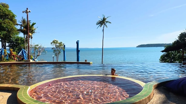 Une piscine à débordement offrant une vue imprenable sur l’océan, avec un palmier en arrière-plan.