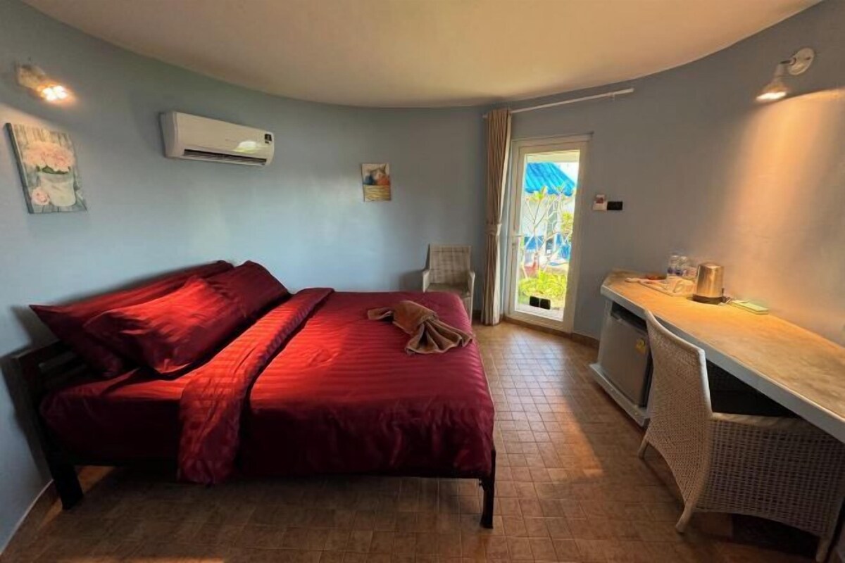 A bedroom with a bed, a desk, and a window.