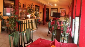 A restaurant with a bar area, multiple tables and chairs, and potted plants. - Hotel-Restaurant Rosengarten (Zell am Ziller)