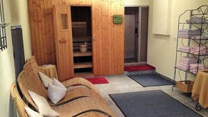 A cozy room with a wicker sofa, a small table, a metal towel rack, and a shower area. - Hotel-Restaurant Rosengarten (Zell am Ziller)