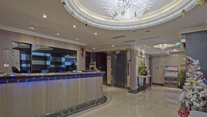 Eine Hotelhalle mit einer Rezeption, einer Chandelüster und einem Weihnachtsbaum.