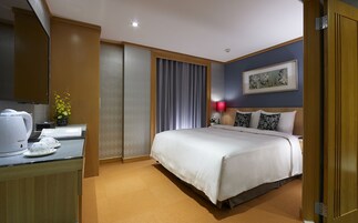 Een hotelkamer met een bed, een bureau met een waterkoker, een lamp en een schilderij aan de muur.