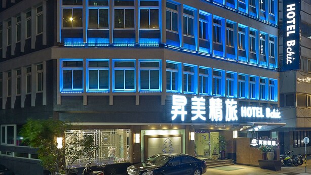 Ein mehrstöckiges Hotel mit blau beleuchteten Fensterrahmen und einem Schild mit der Aufschrift 'Aisle Beauty Hotel'.